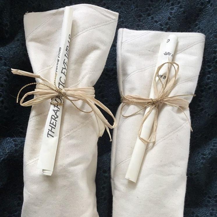 2 soft white rectangular eye wraps, tied up with string